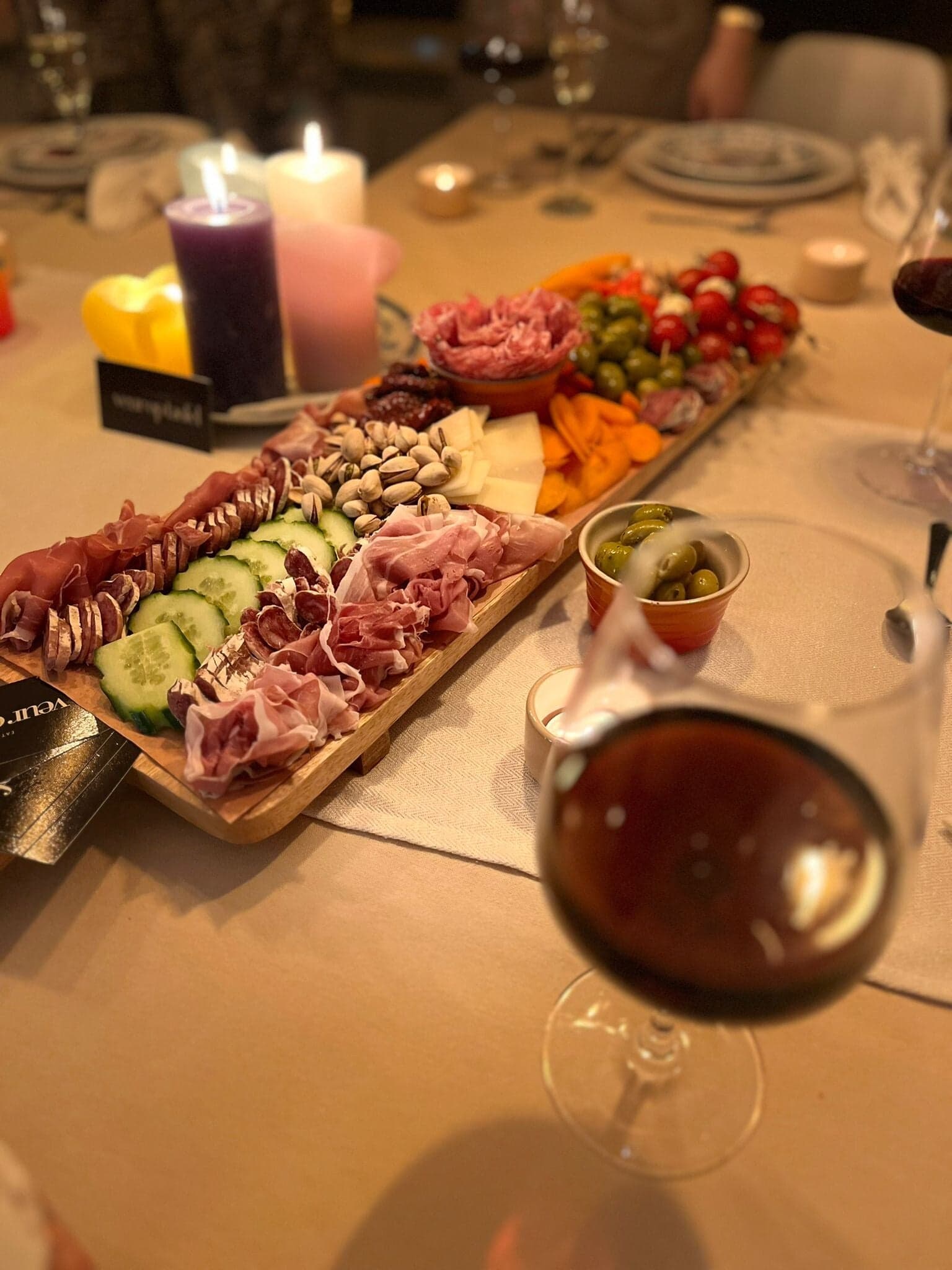 Borrelplank bij kaarslicht met een glas rode wijn